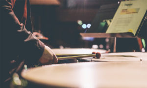 a percussionist strikes a drum with their mallets