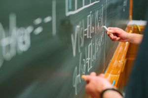 students writing on chalkboard